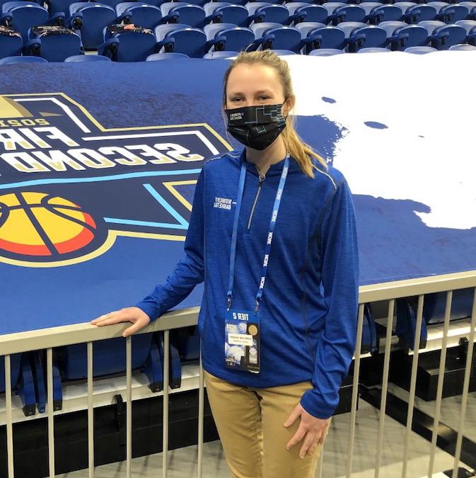 Student standing in front of an NCAA sign in an arena